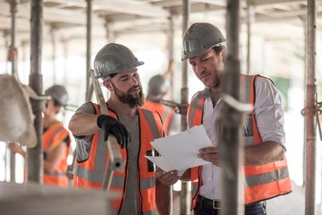 Male builders looking at blueprint on construction site
