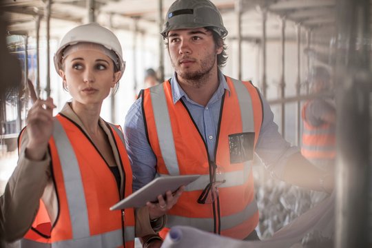 Female and male builders using digital tablet on construction site