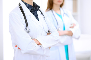 Close up of unknown female doctor standing in a hospital with her colleague in the background