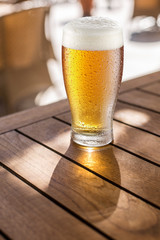 Glass of light beer on the wooden table.