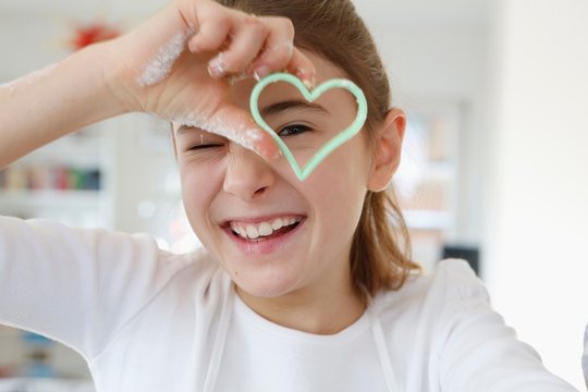 Girl looking through heart shaped cookie cutter smiling