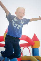 Excited jumping boy near bouncy castle outdoors