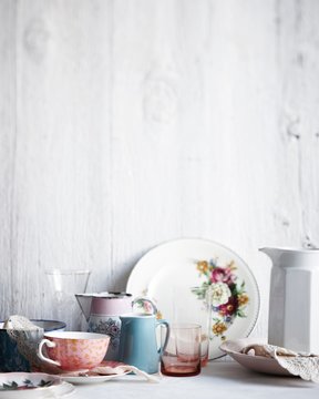 Variety of drinking glasses, plates and jugs on whitewashed table