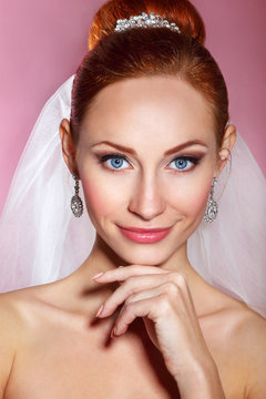 Bridal Beauty .Beautiful young woman with professional make up ..Bride's portrait on a pink background.Youth and Skin Care Concept.Girl with red hair
