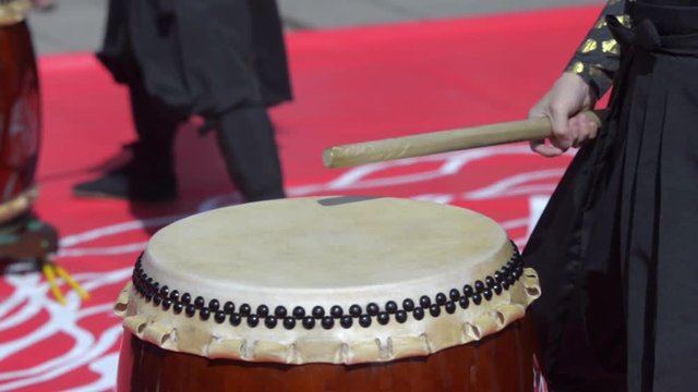 Japanese artist is drumming on traditional taiko drums. Drumsticks beating on a traditional drum
