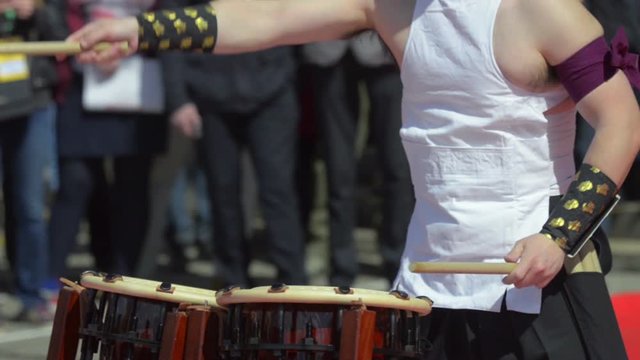 Japanese artist is drumming on traditional taiko drums. Drumsticks beating on a traditional drum