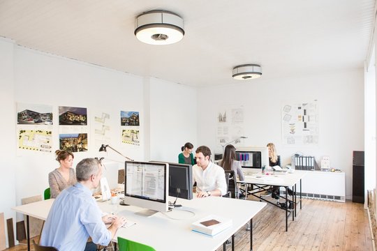 Colleagues in office sitting at desks using computers