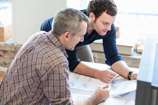 High angle view of men in office discussing paperwork