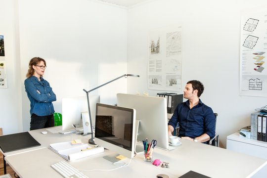 Colleagues in office using computer chatting