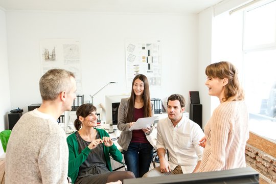 Colleagues in office discussing paperwork smiling
