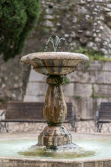 Fontana antica in pietra con al centro un piedistallo con catino  da cui sgorga l’acqua