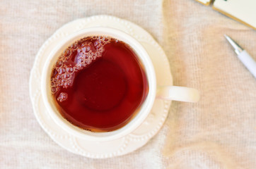 A cup of tea on the table with a tablecloth. Top view