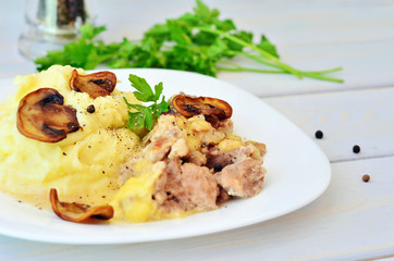 Mashed potatoes with meat. Puree with pork and mushrooms on a table next to the beam parsley
