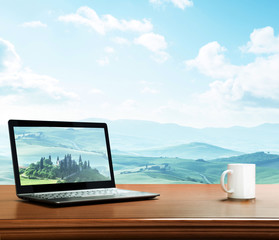 notebook and cup on table, tuscany, Italy as background
