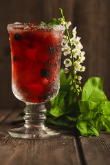 Berry soft drink with ice on a wooden background and flowers