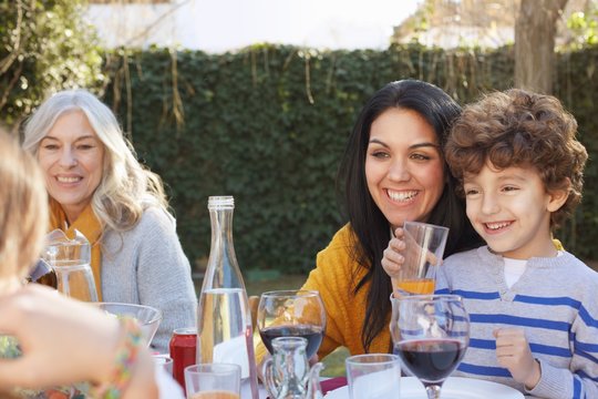 Multi generation family dining outdoors, smiling