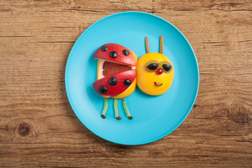 Ladybird made of fruits on brown wood
