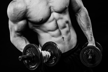 Close up of muscular bodybuilder guy doing exercises with weights dumbbell over isolated black...
