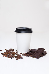 paper cup with coffee and pieces of chocolate on white backgroun