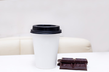 paper cup with coffee and chocolate chips are on the table