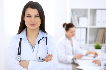 Fototapeta premium Brunette female doctor on the background of colleagues talking to each other in hospital