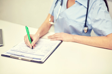 close up of female doctor writing prescription