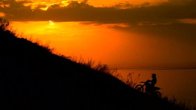On the way to achieve the goal. motocross bike at sunset on hill climbs. 