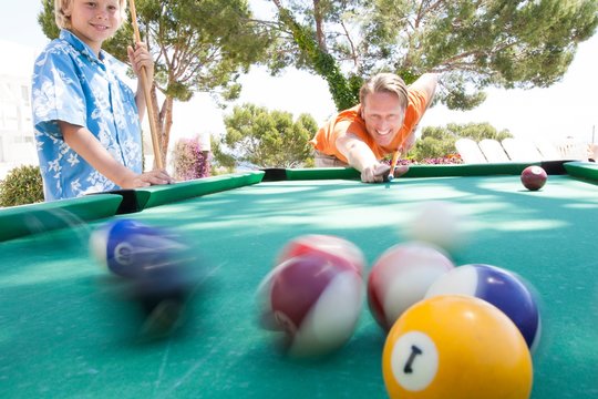 Father and son playing pool outdoors