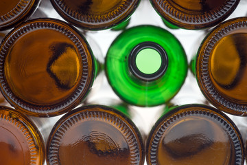 Glass green bottle among brown bottles. Concept of difference