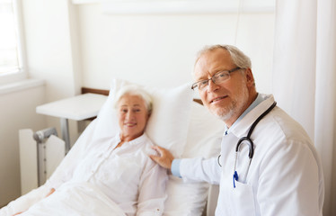 doctor visiting senior woman at hospital ward