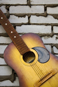 Acoustic guitar resting against a brick background