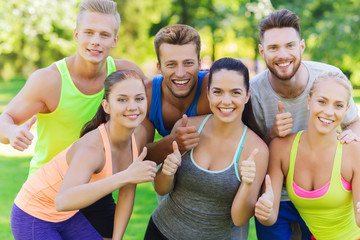 group of happy sporty friends showing thumbs up