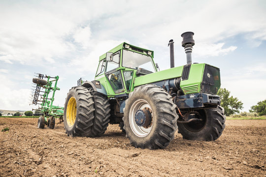 Farmer driving tractor and plough in ploughed field