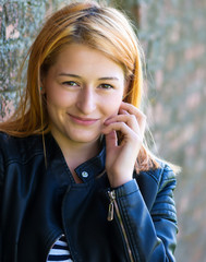 Portrait of a smiling, beautiful young woman leaning against a wall