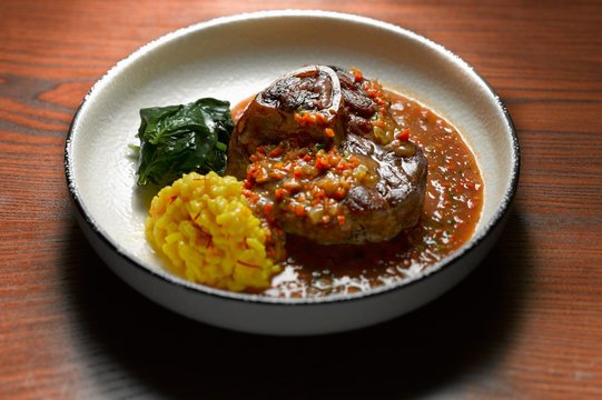 High angle view of ossobuco with side dish of vegetables in shallow bowl