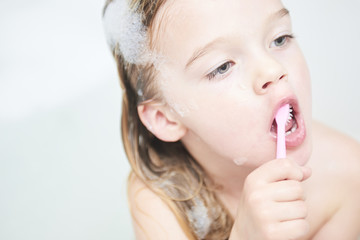 Dental hygiene. Close up of little girl brushing her teeth. Fun in the bath