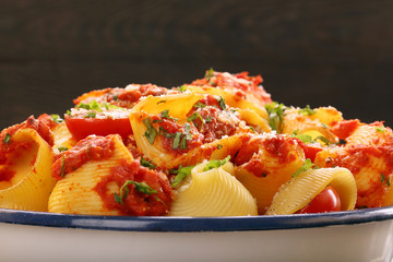 Lumaconi pasta with tomato sauce on wooden background
