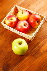 Red apples in basket on wooden table