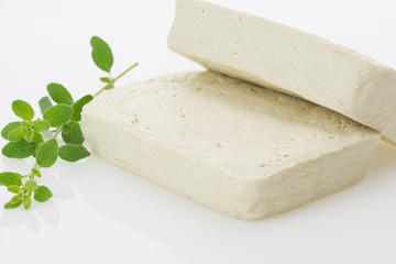 Tofu blocks with fresh oregano, isolated on white background.