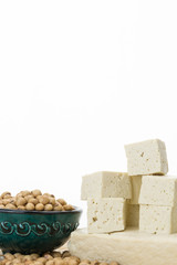 Tofu block and cut cubes with soybeans in bowl,  on white background with copy-space