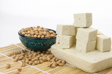 Tofu block and cut cubes with soybeans in bowl,  on white background with copy-space