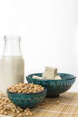 Tofu cut into cubes with soybeans in bowl and soy milk,  on white background with copy-space