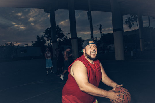 Mid adult man wearing vest playing basketball open mouthed smiling