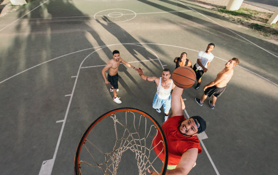 High angle view of young man on basketball court doing slam dunk