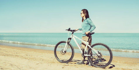Fototapeta na wymiar Girl with bicycle on beach