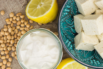Soy mayonnaise, lemon, soybeans and tofu, on wooden background