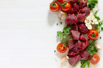 A raw fresh meat, spices and vegetables on a light wooden backgr