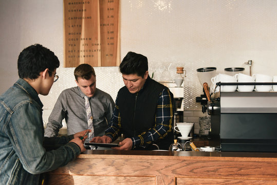 Manager checking digital tablet for customer at coffee shop counter