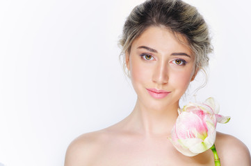 Obraz na płótnie Canvas Young beautiful woman with healthy face and nude makeup posing with delicate pink flower on white background