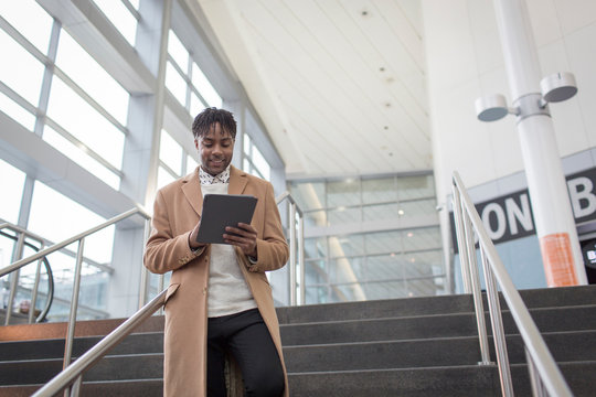 Young businessman using digital tablet moving down train station stairway